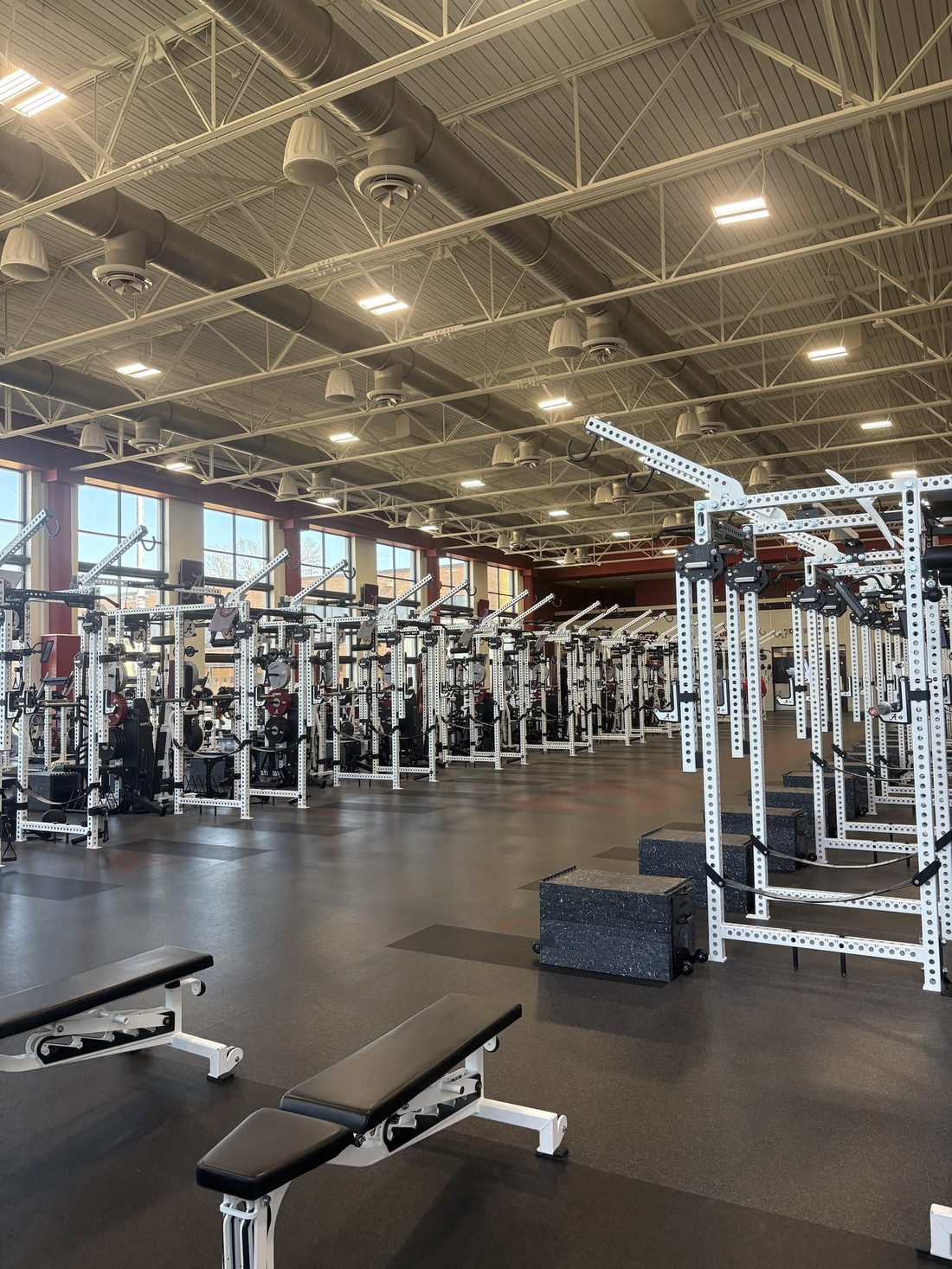 Rows of racks and benches in a college strength and conditioning room